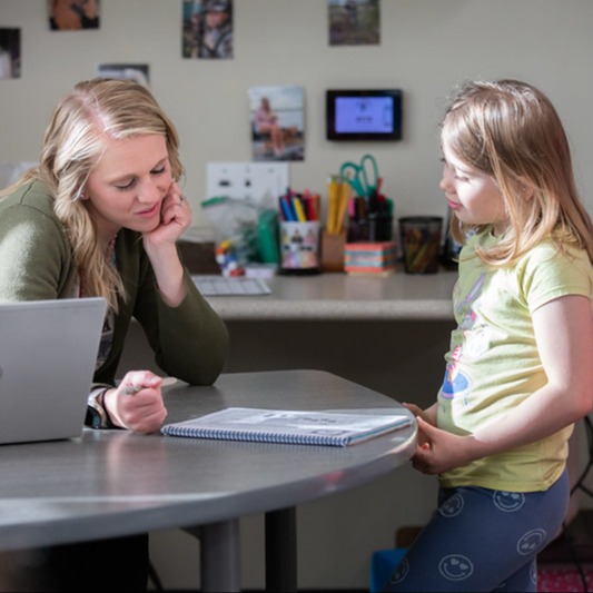 teacher working with elementary student at desk