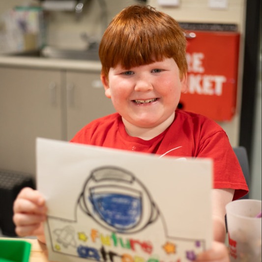 student smiling and holding up a picture that reads future astronaut