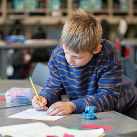 student wroking at desk with pencil and paper