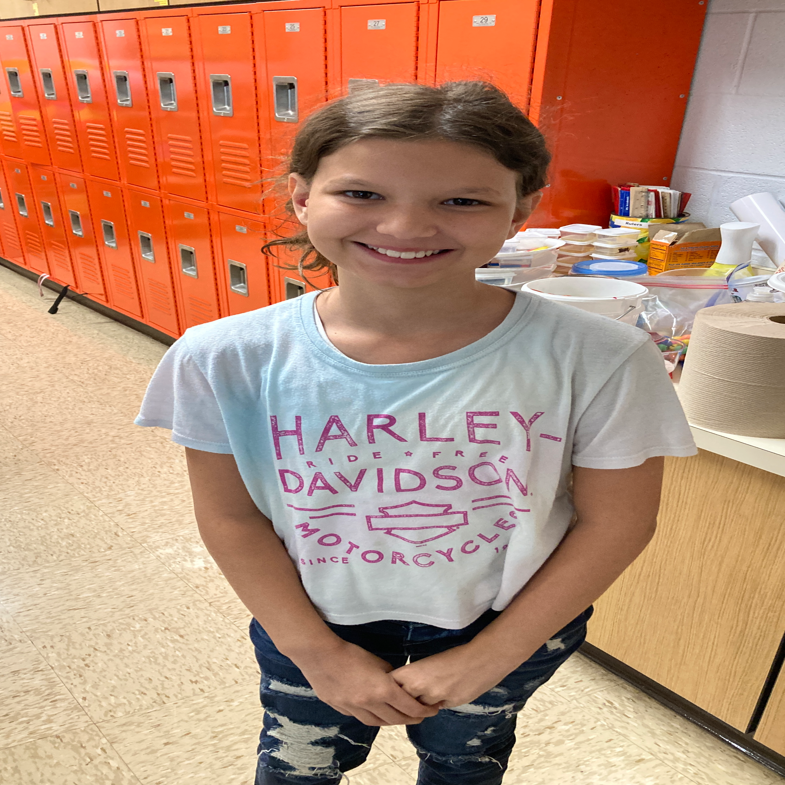 smiling girl with dark pulled back  hair in a pink and blue Harley Davidson t-shirt