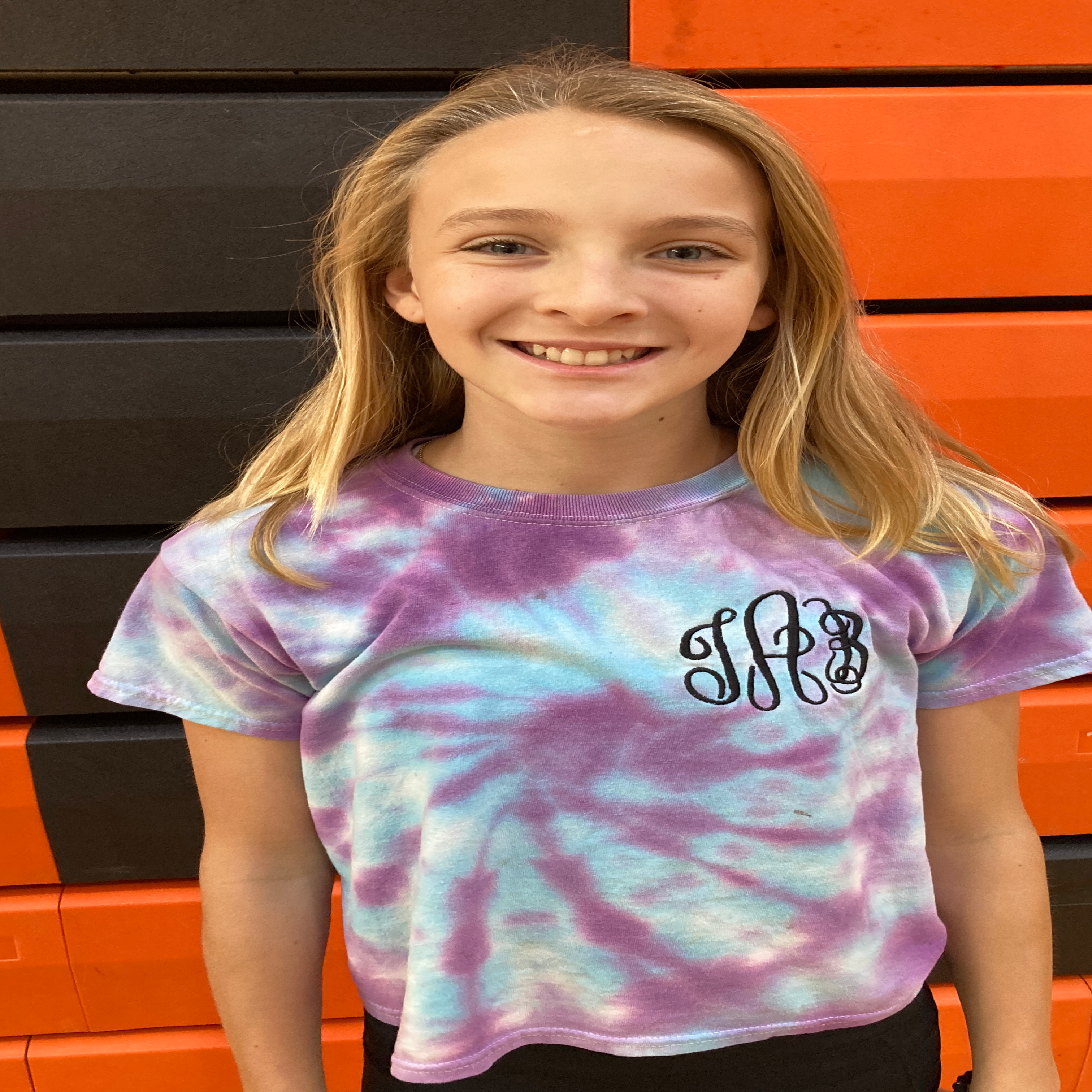 grinning teen girl with blonde hair in a tie-dye  t-shirt