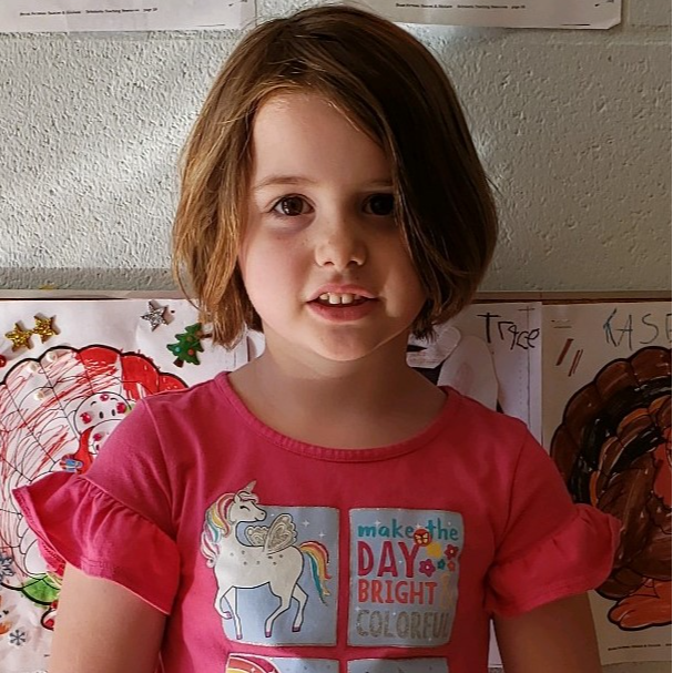 Young girl with short, dark blonde hair and pink shirt
