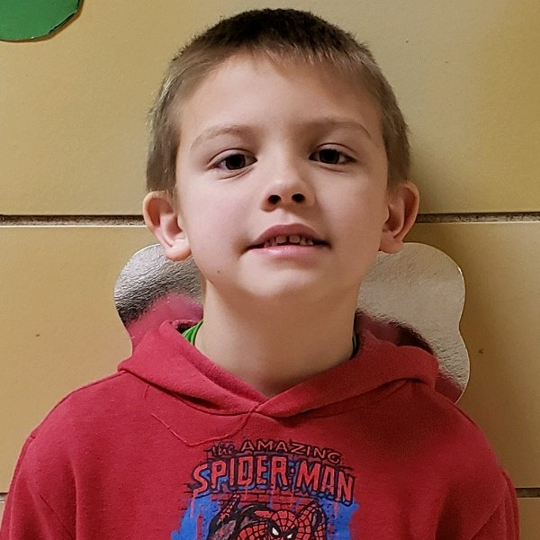 young boy with dark blonde hair wearing a red spiderman hoodie