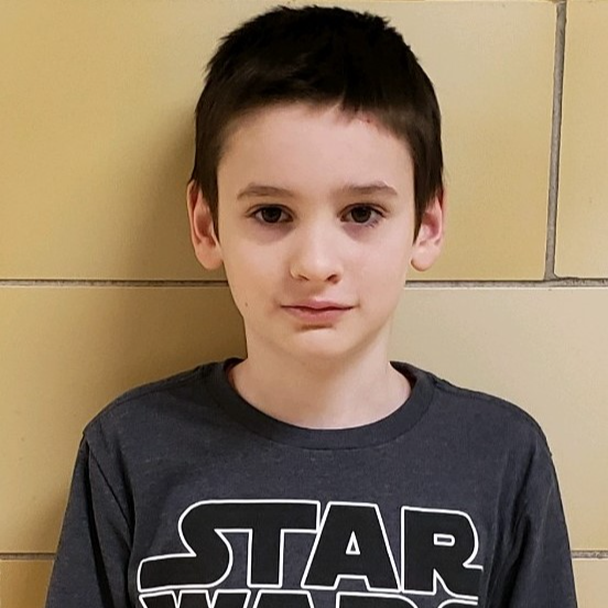 young boy with  dark  hair  wearing a gray "Star Wars"  t-shirt 