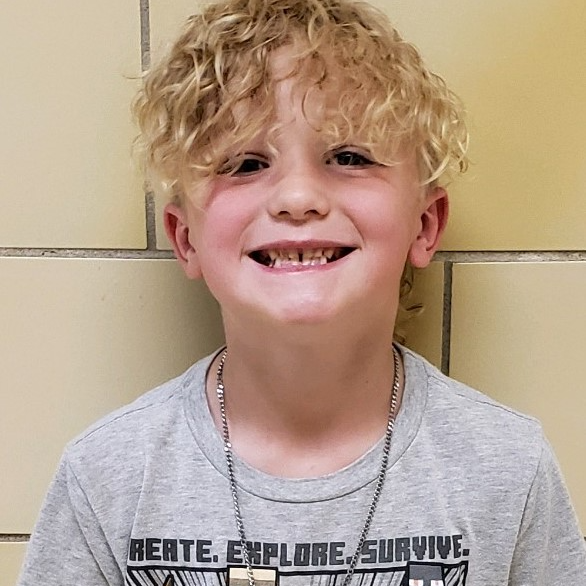 boy with curly blonde hair wearing a gray t-shirt