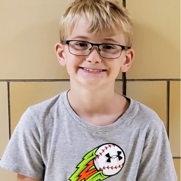 smiling boy with blonde hair and glasses wearing a gray t-shirt