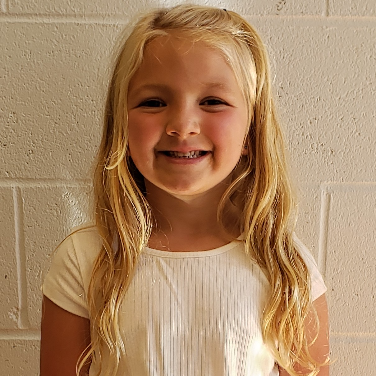 young girl with long blonde hair  wearing a white shirt