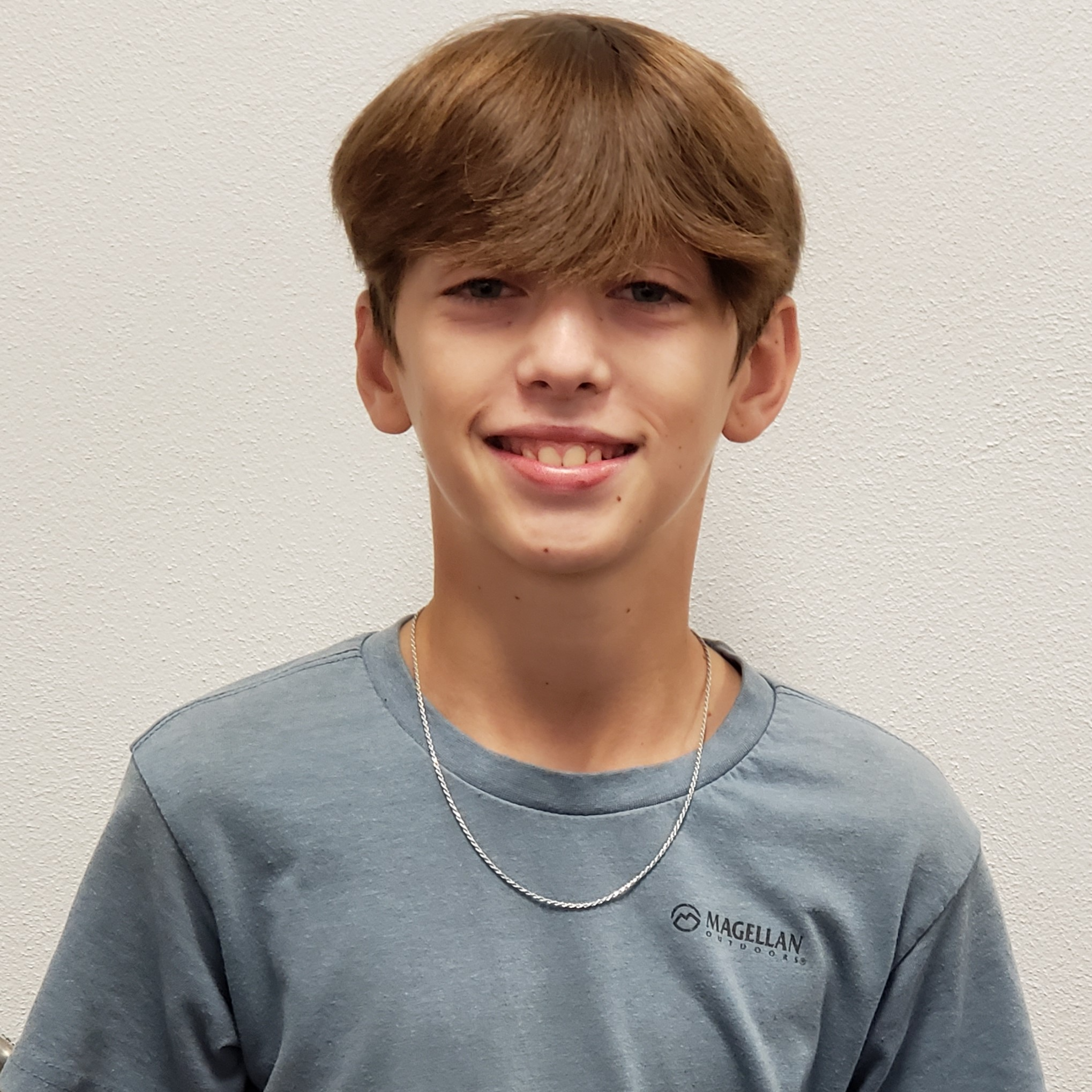 smiling boy with brown hair wearing a gray t-shirt