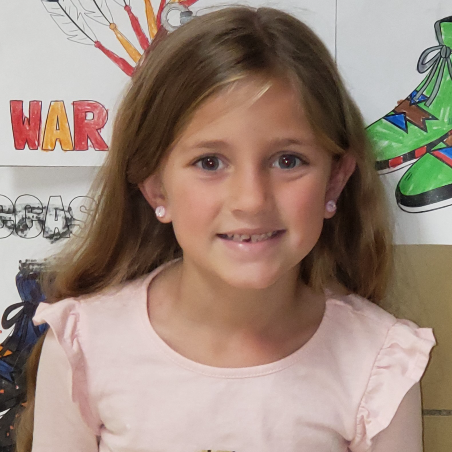 smiling girl with dark blonde hair wearing a pink shirt