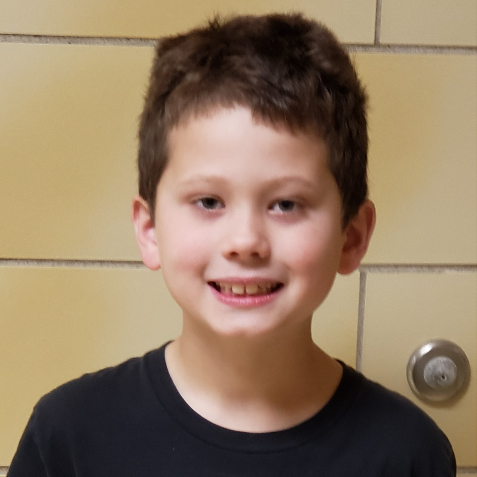smiling boy with brown hair wearing a black t-shirt