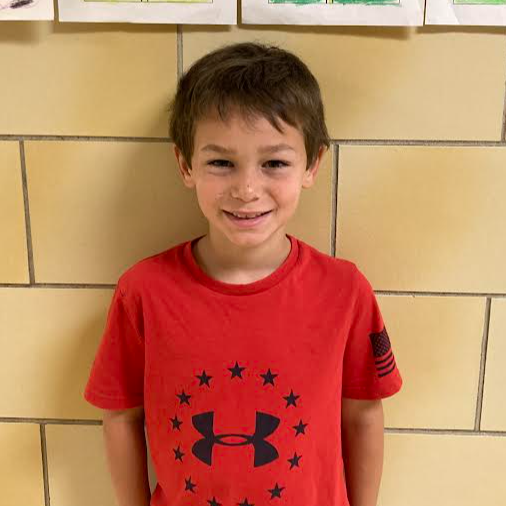 smiling young boy with brown hair and a red/black under armour t-shirt