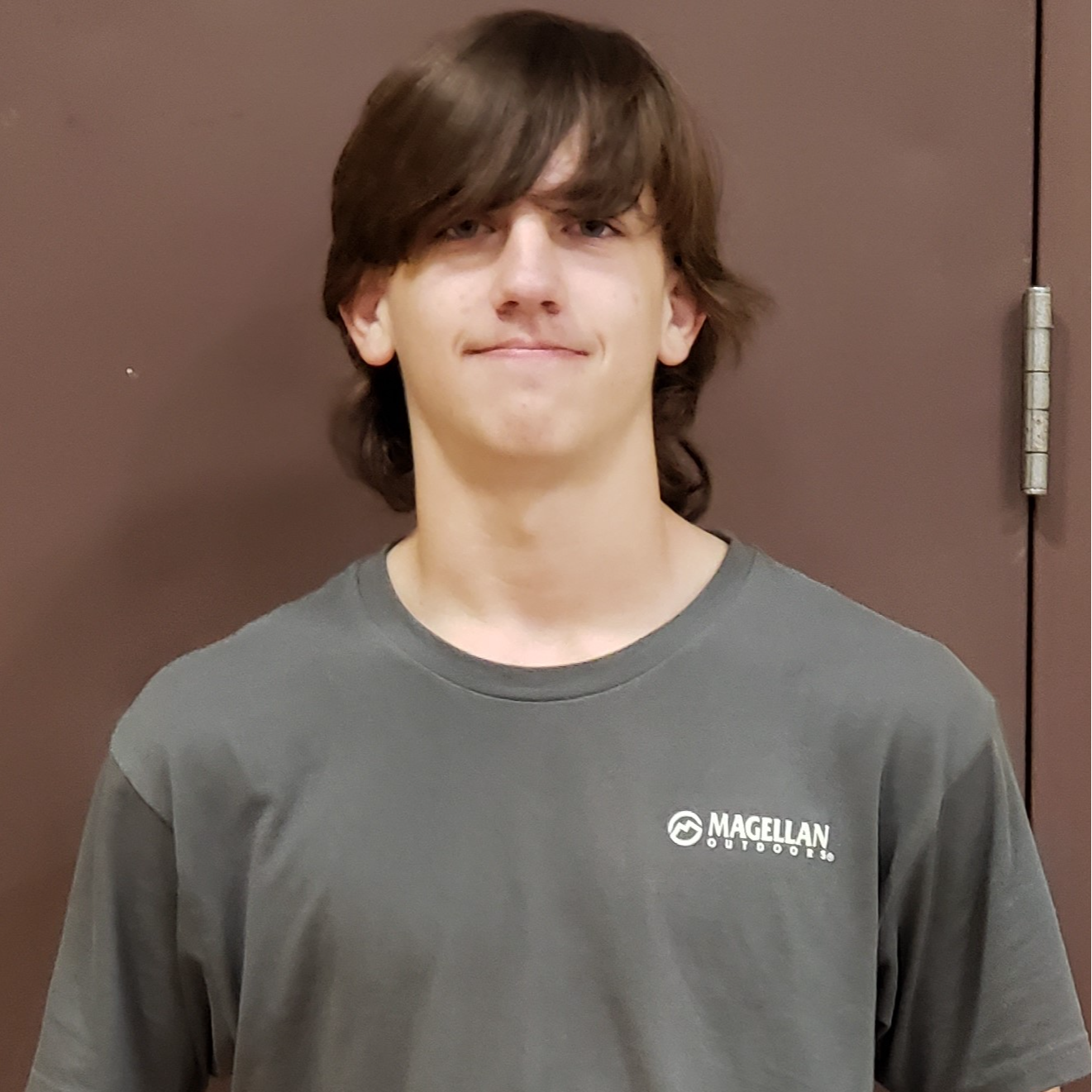 young man with brown hair hanging in his eyes wearing a dark gray t-shirt