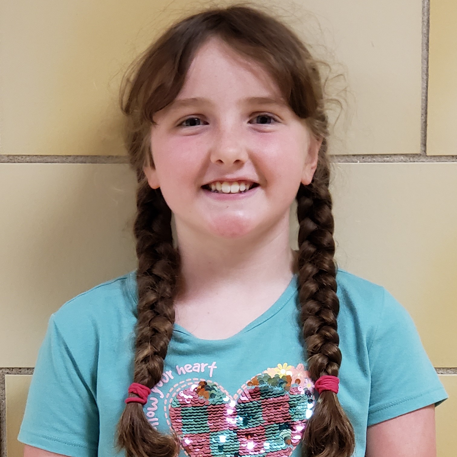 smiling girl with brown braids wearing a light blue t-shirt