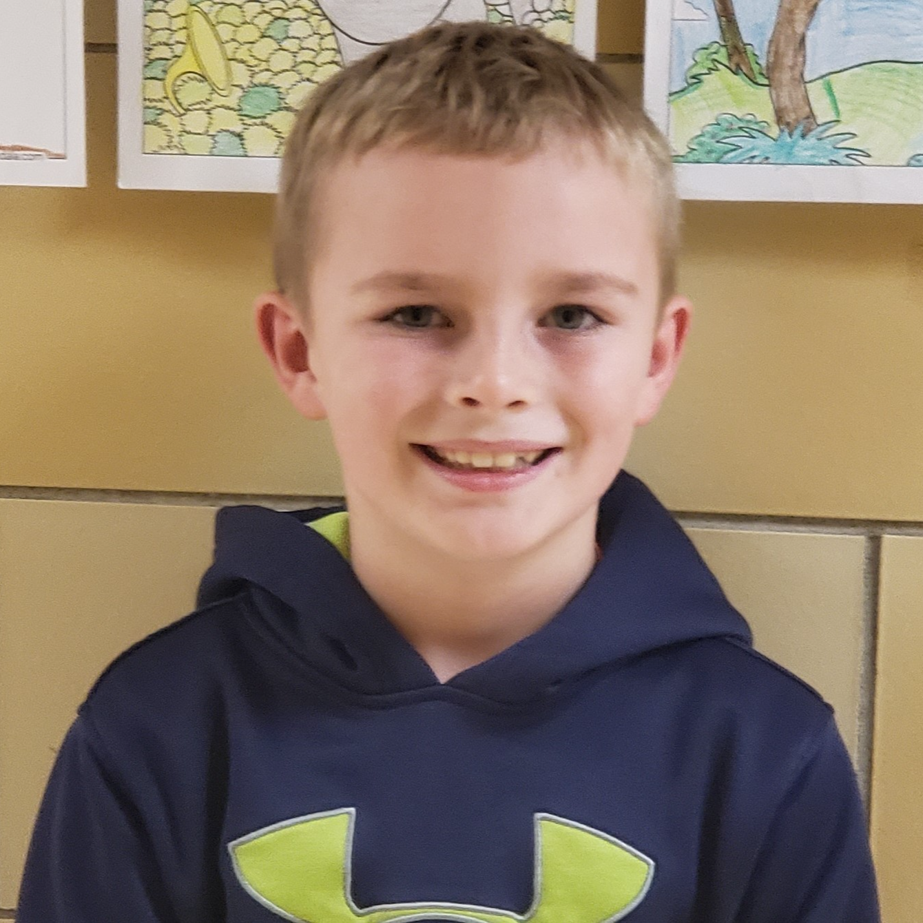 smiling boy with blonde hair wearing a navy blue hoodie