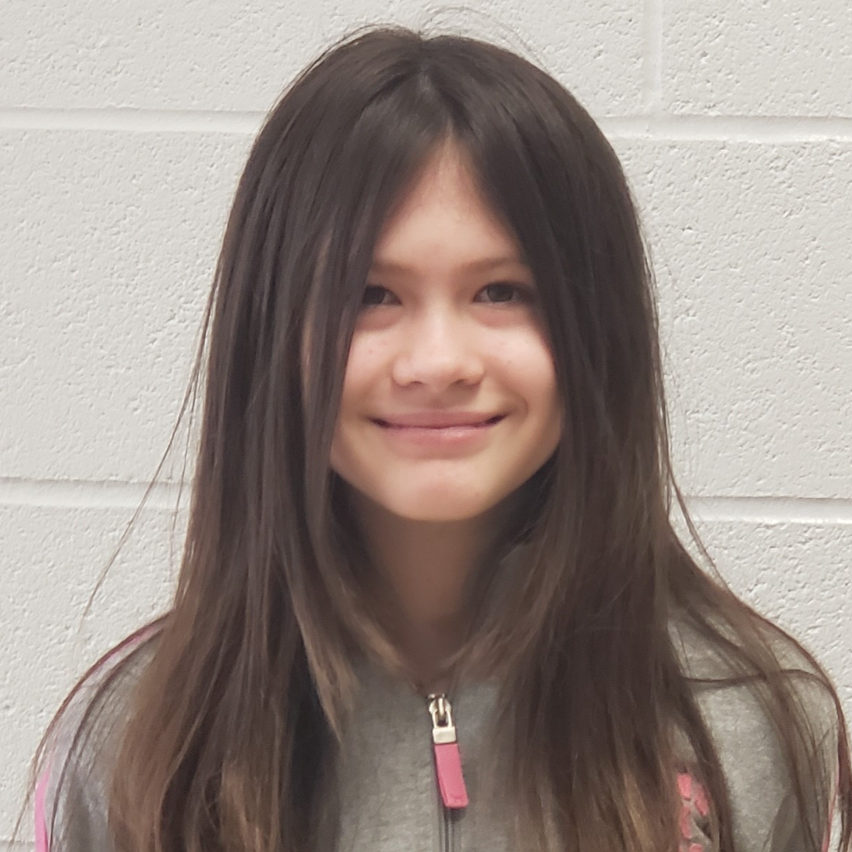 girl with long dark hair  wearing a  gray jacket zipped up