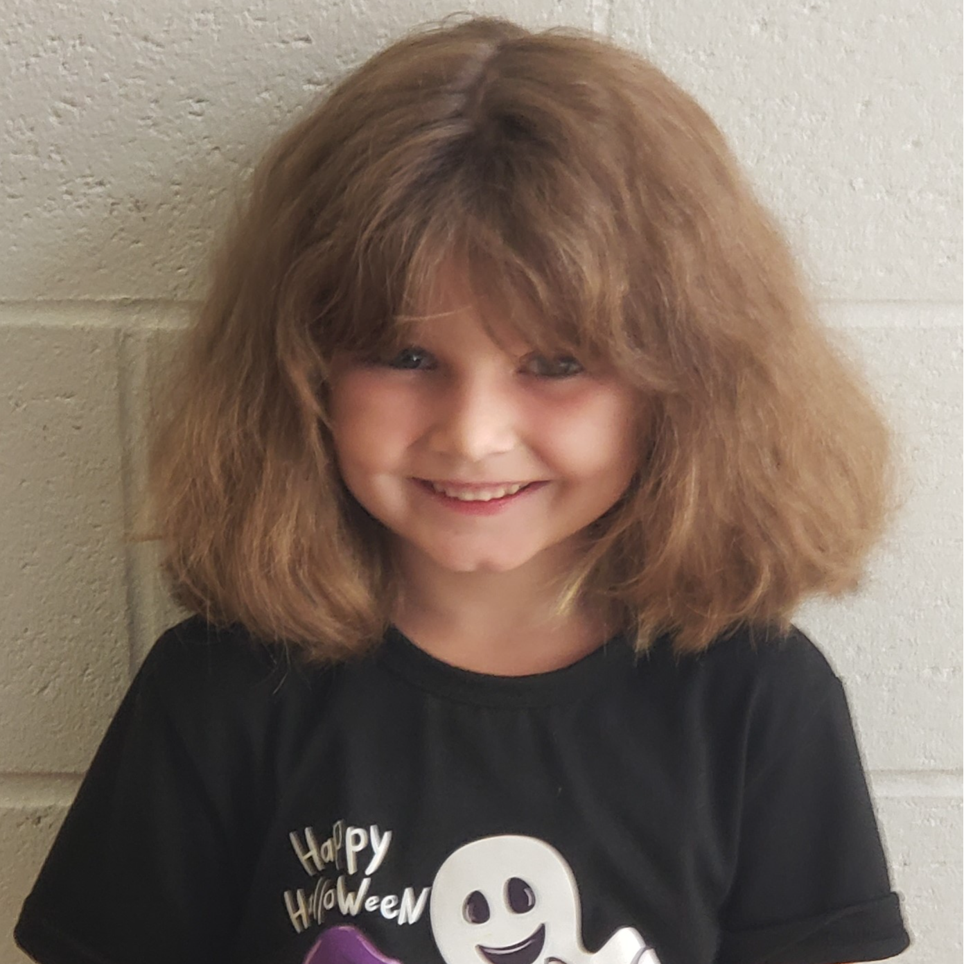 young girl with bushy light brown hair wearing a black Halloween t-shirt