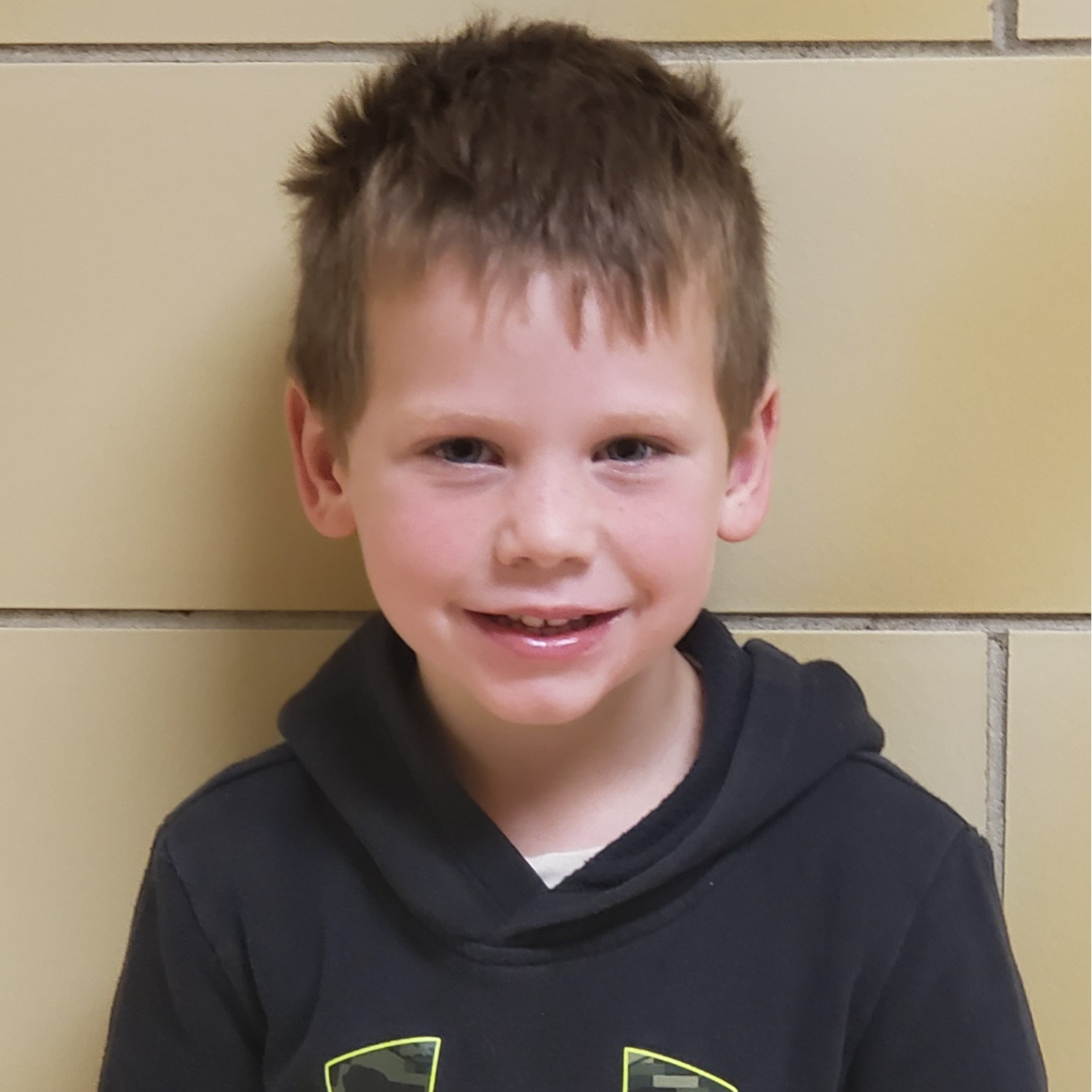 young boy with spiky light brown hair wearing a black hoodie