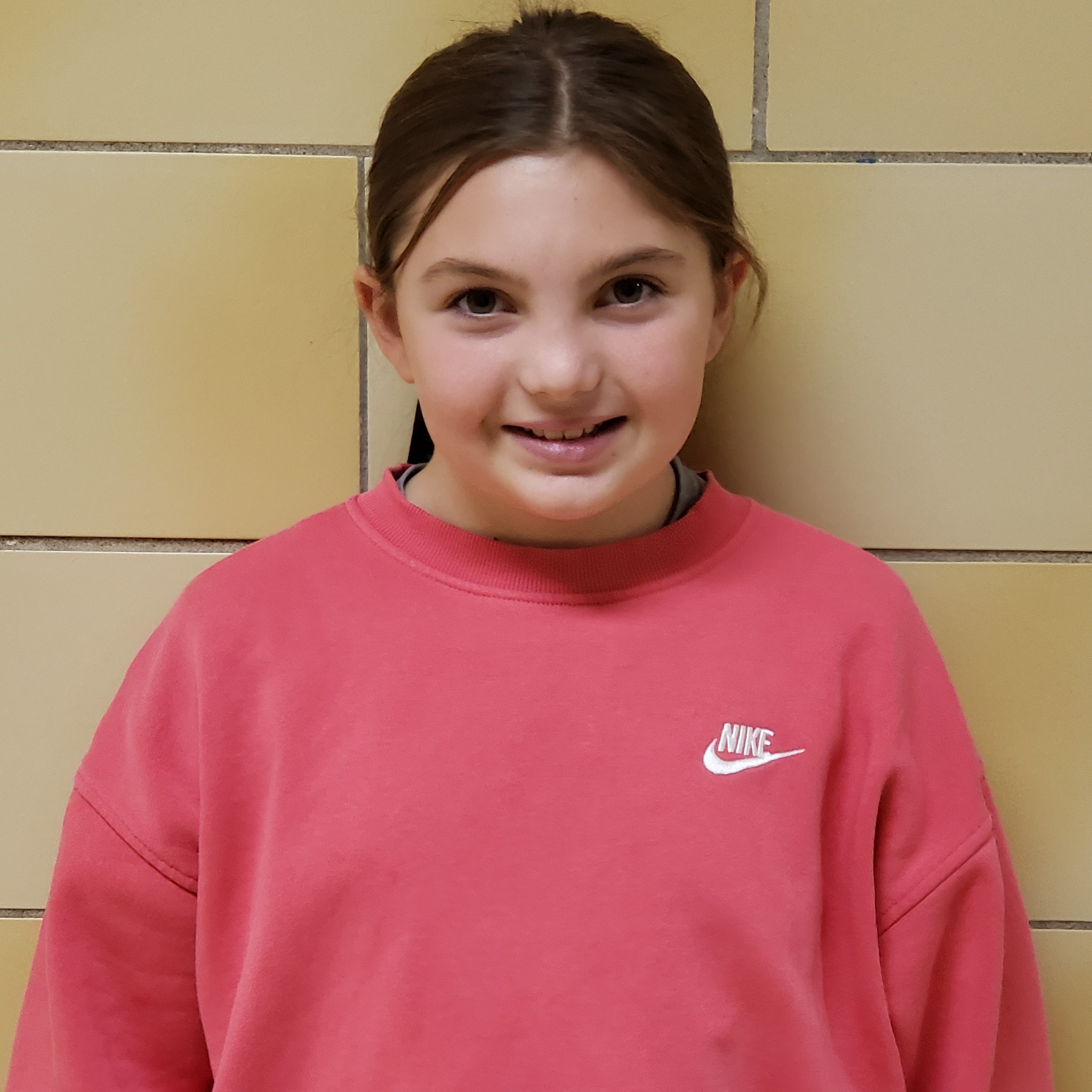 smiling girl with brown hair pulled back wearing a pink Nike sweatshirt