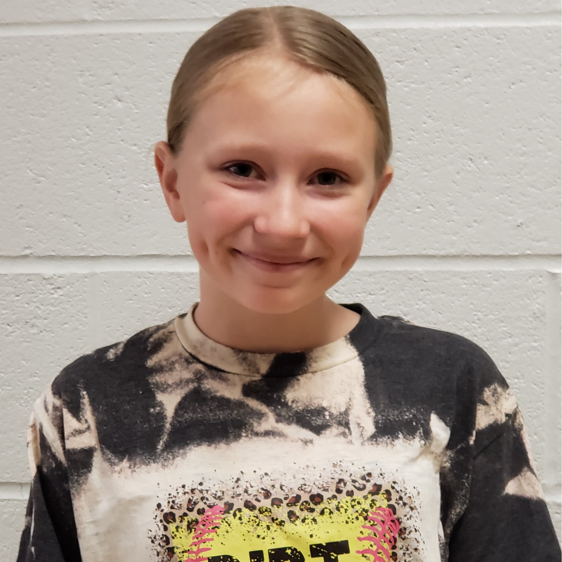 smiling girl with dimples & dark blonde hair pulled back wearing a bleached black t-shirt