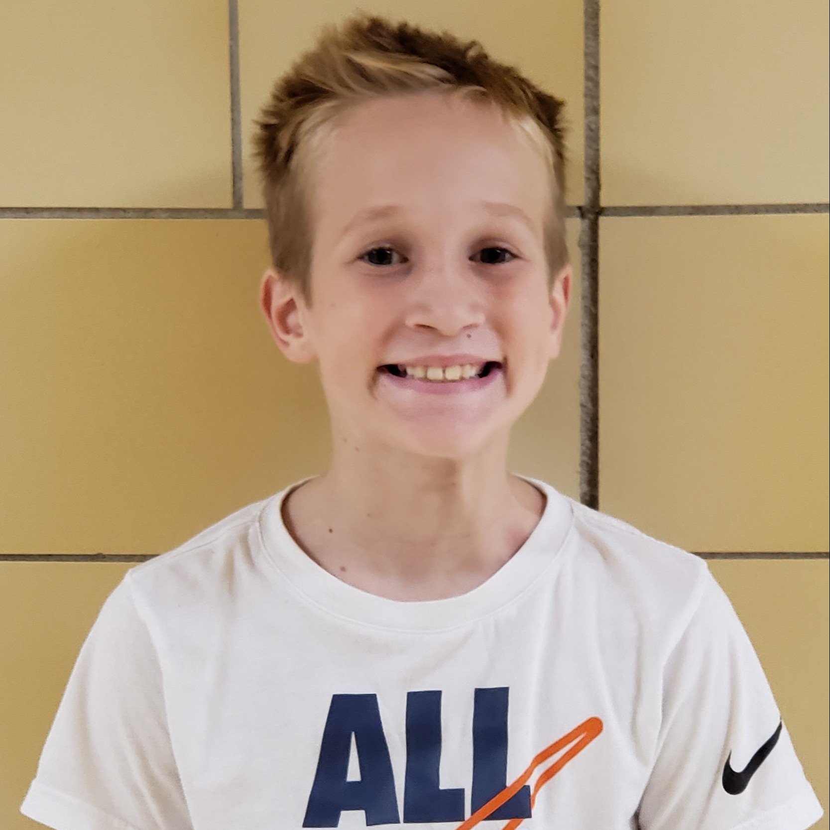 smiling boy with spiky blonde hair wearing a white t-shirt