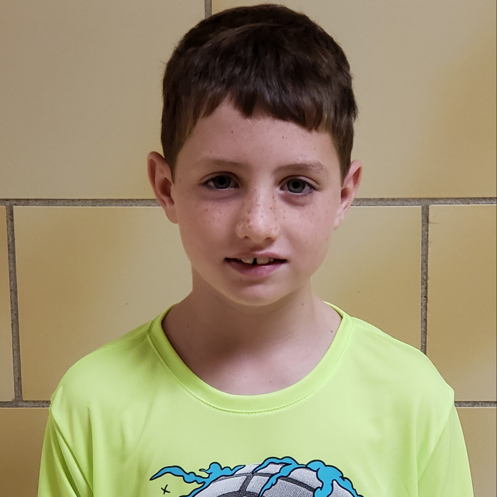 boy with dark hair and freckles wearing a chartreuse t-shirt