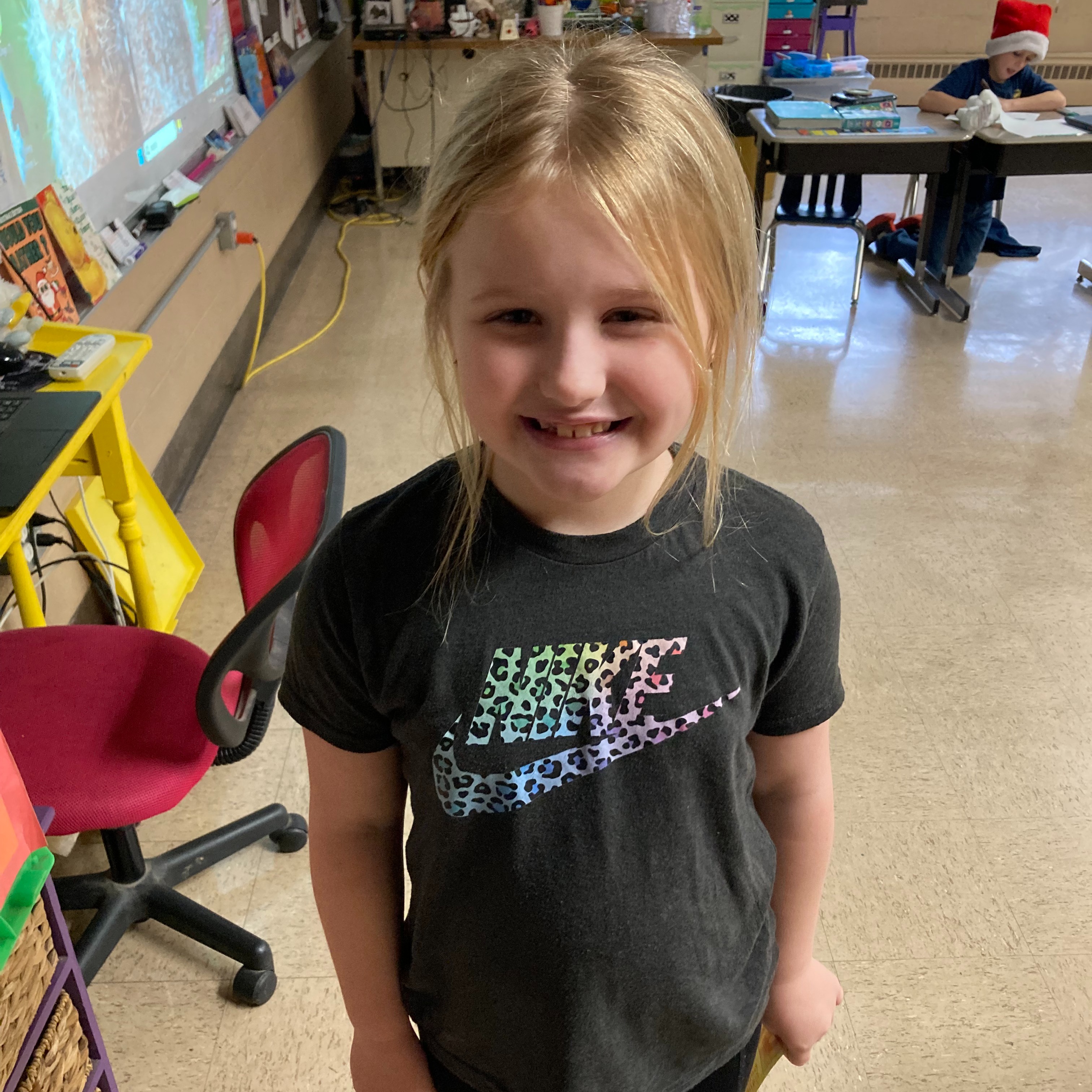 smiling young girl with blonde hair wearing a colorful cheetah print nike shirt