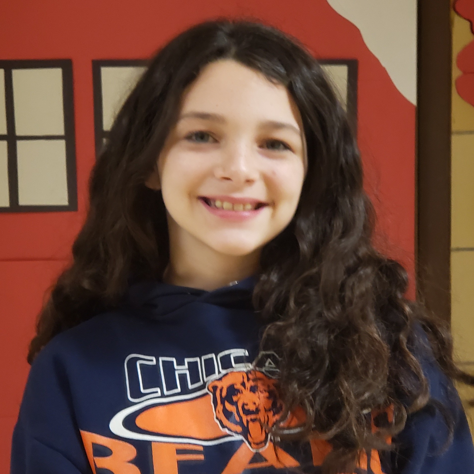 smiling girl with long dark hair wearing a navy blue Chicago Bears hoodie