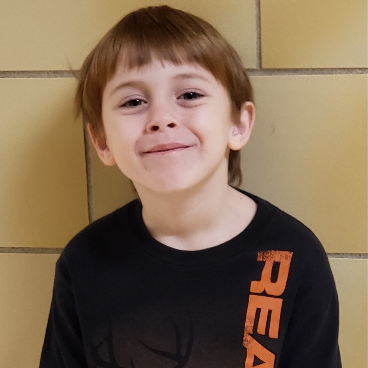 grinning young boy with straight red hair wearing a black t-shirt