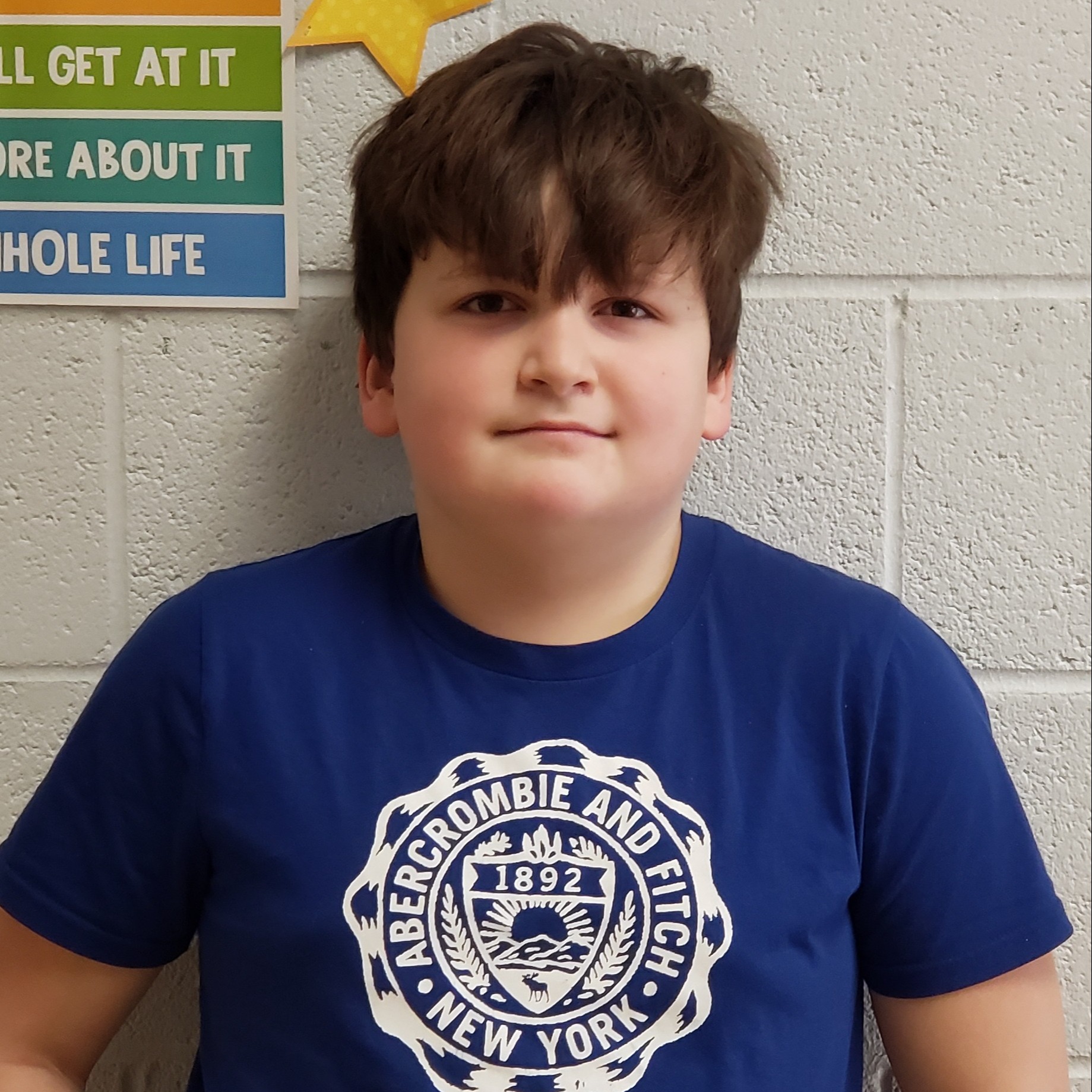 smiling boy with dark hair wearing a blue t-shirt 