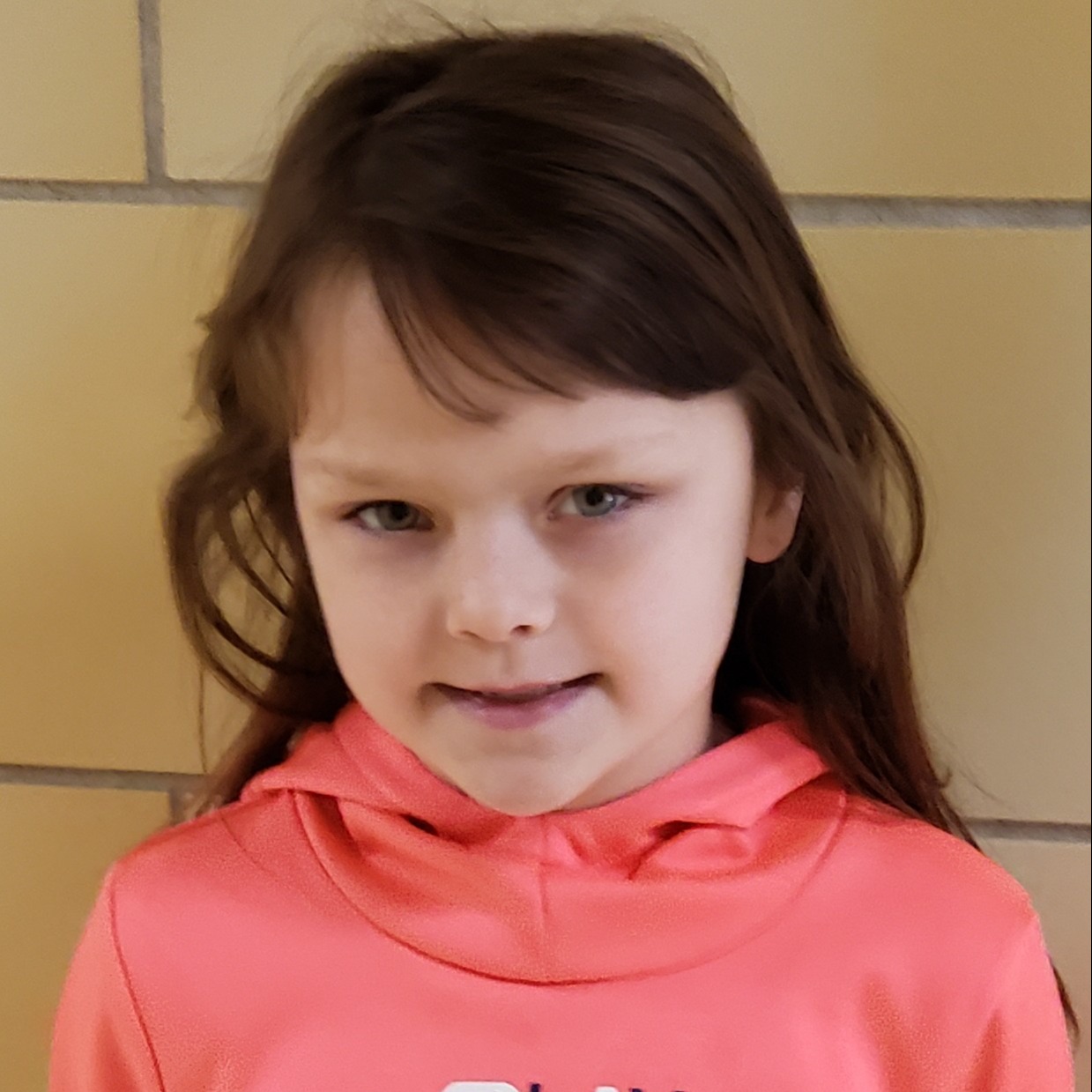 smiling girl with brown hair wearing a coral hooded sweatshirt