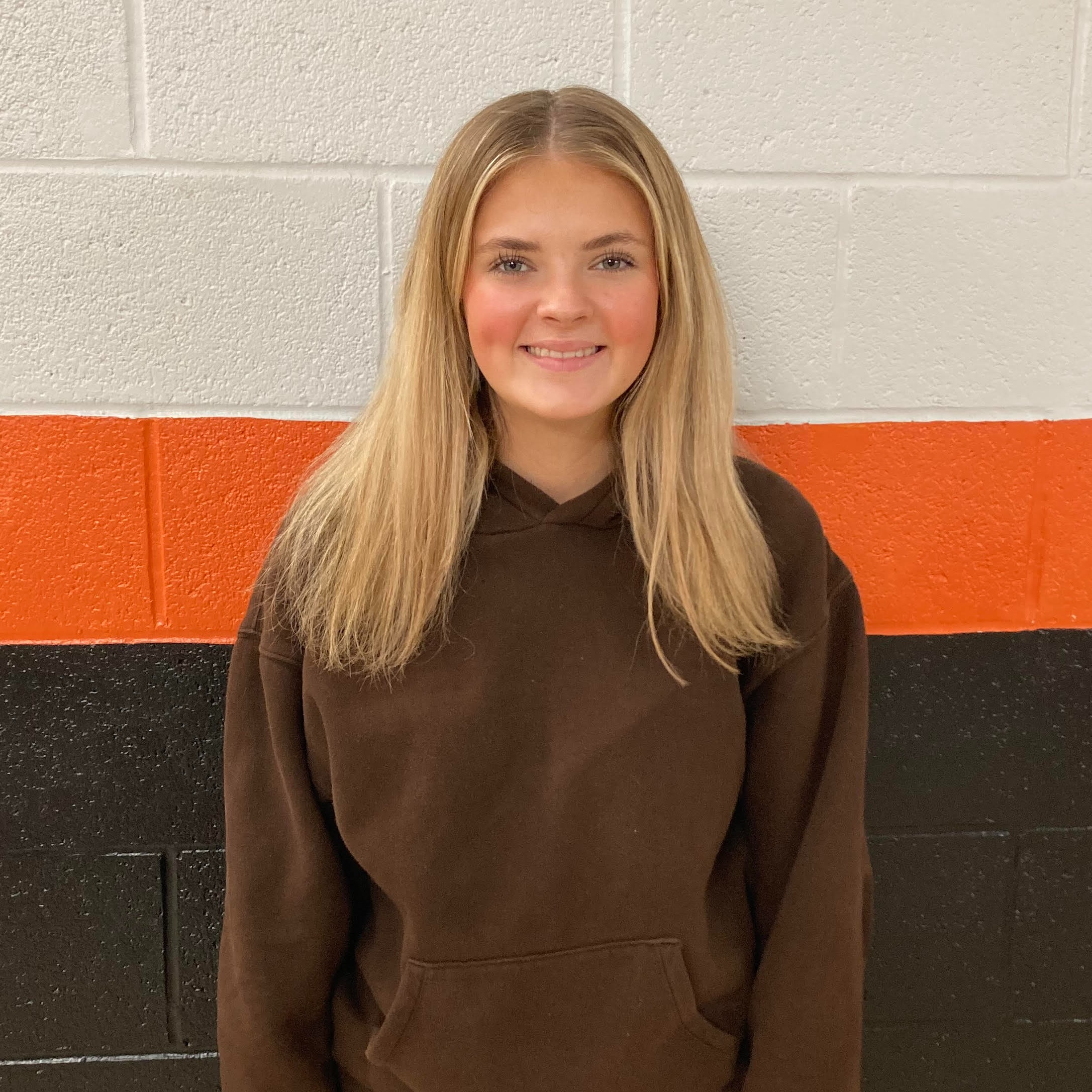 high school female with blonde straight hair wearing a brown hoodie