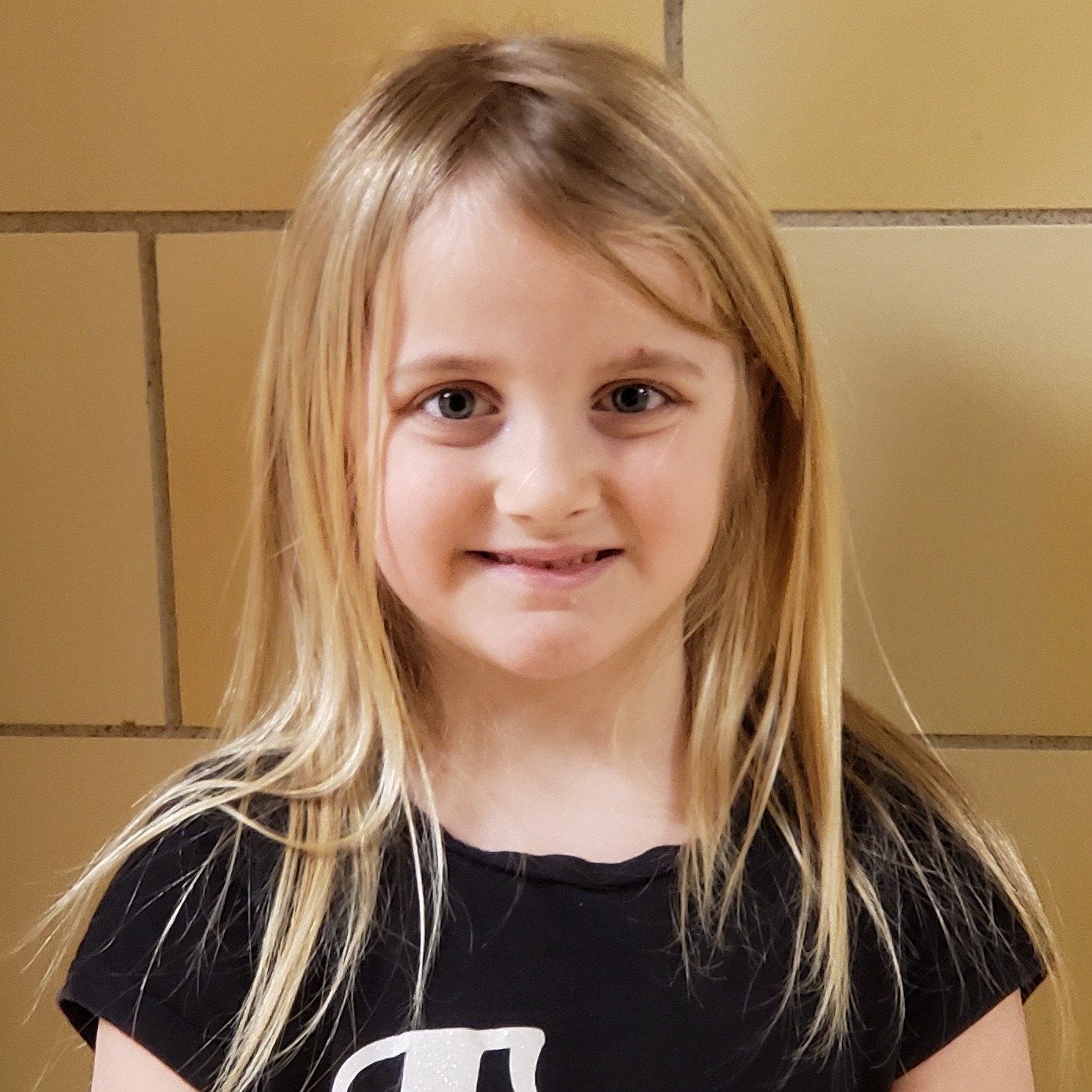 smiling young girl with blonde  hair, wearing a black t-shirt