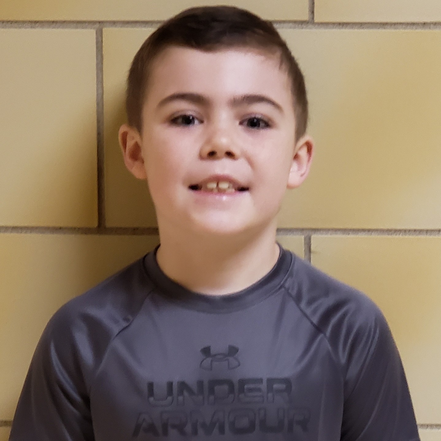 smiling boy with dark hair wearing a dark gray t-shirt