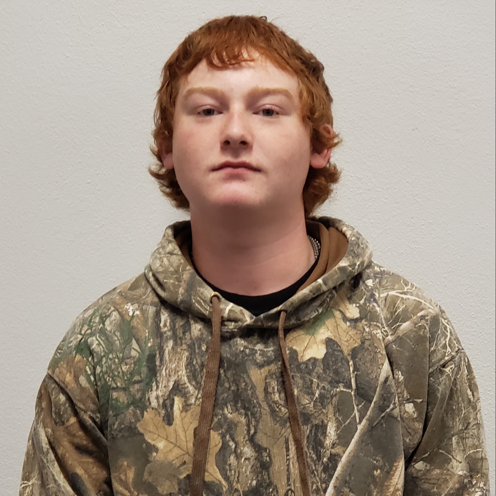 young man with red hair wearing a camouflage hooded sweatshirt 