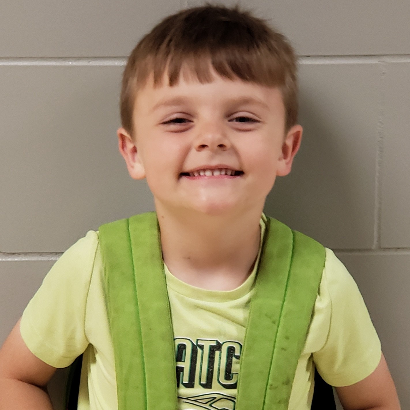 young boy with dark blonde hair wearing a light green t-shirt