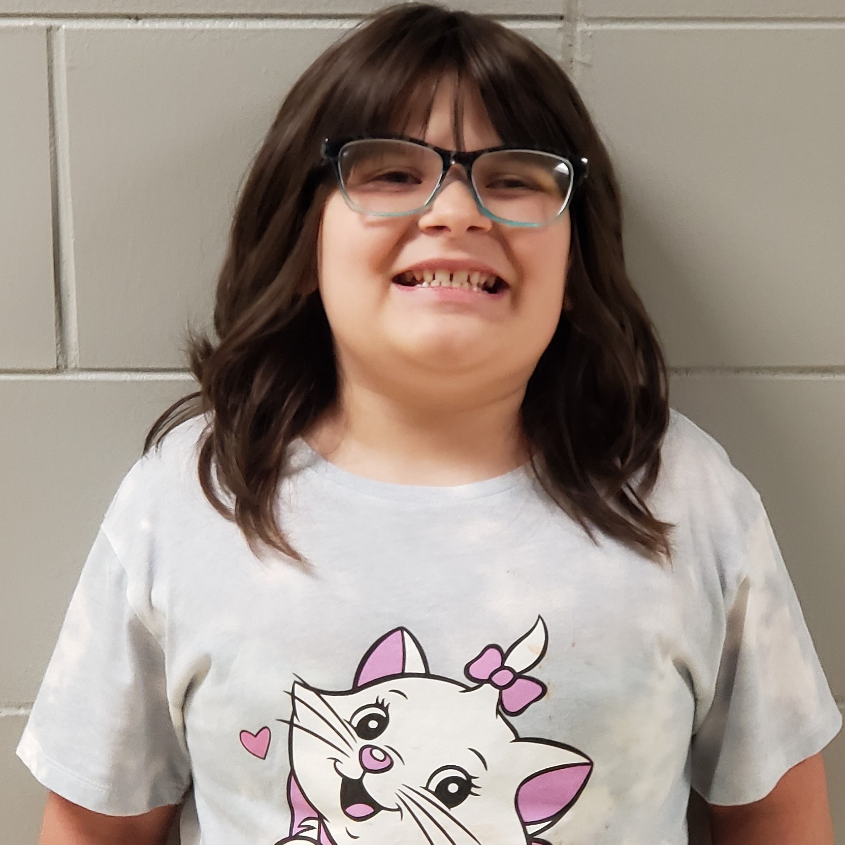young girl with dark brown hair and glasses wearing a white t-shirt with a kitty on it