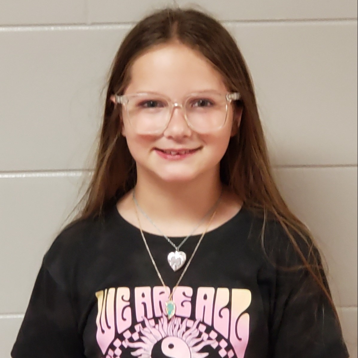 smiling girl with long brown hair and clear glasses wearing a black t-shirt