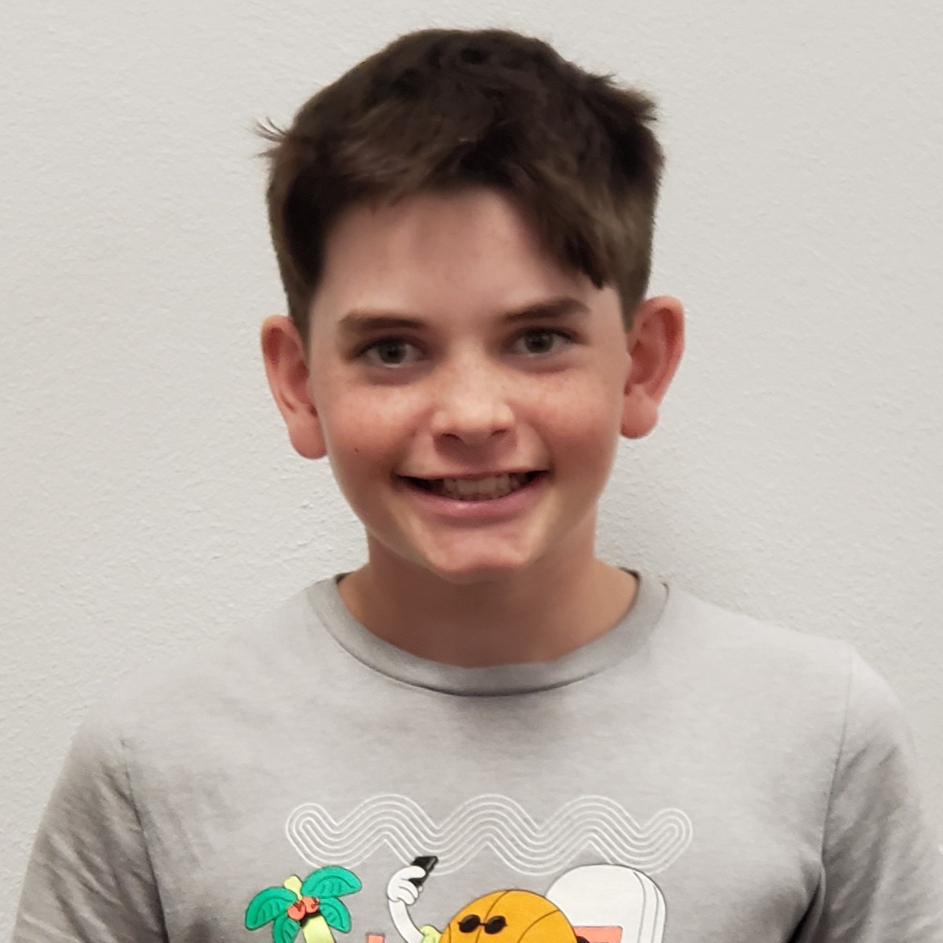 young male with brown hair and freckles wearing a  gray t-shirt