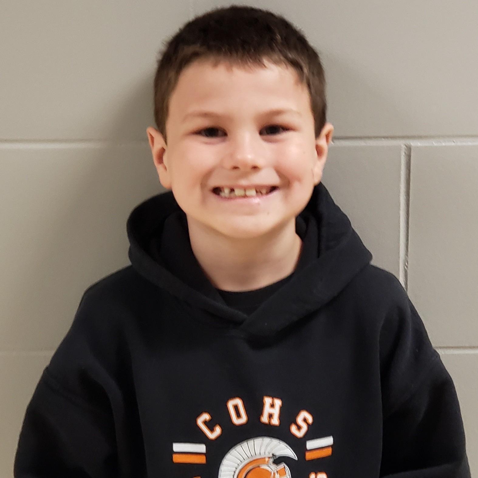 young boy with dark hair wearing a black hooded sweatshirt