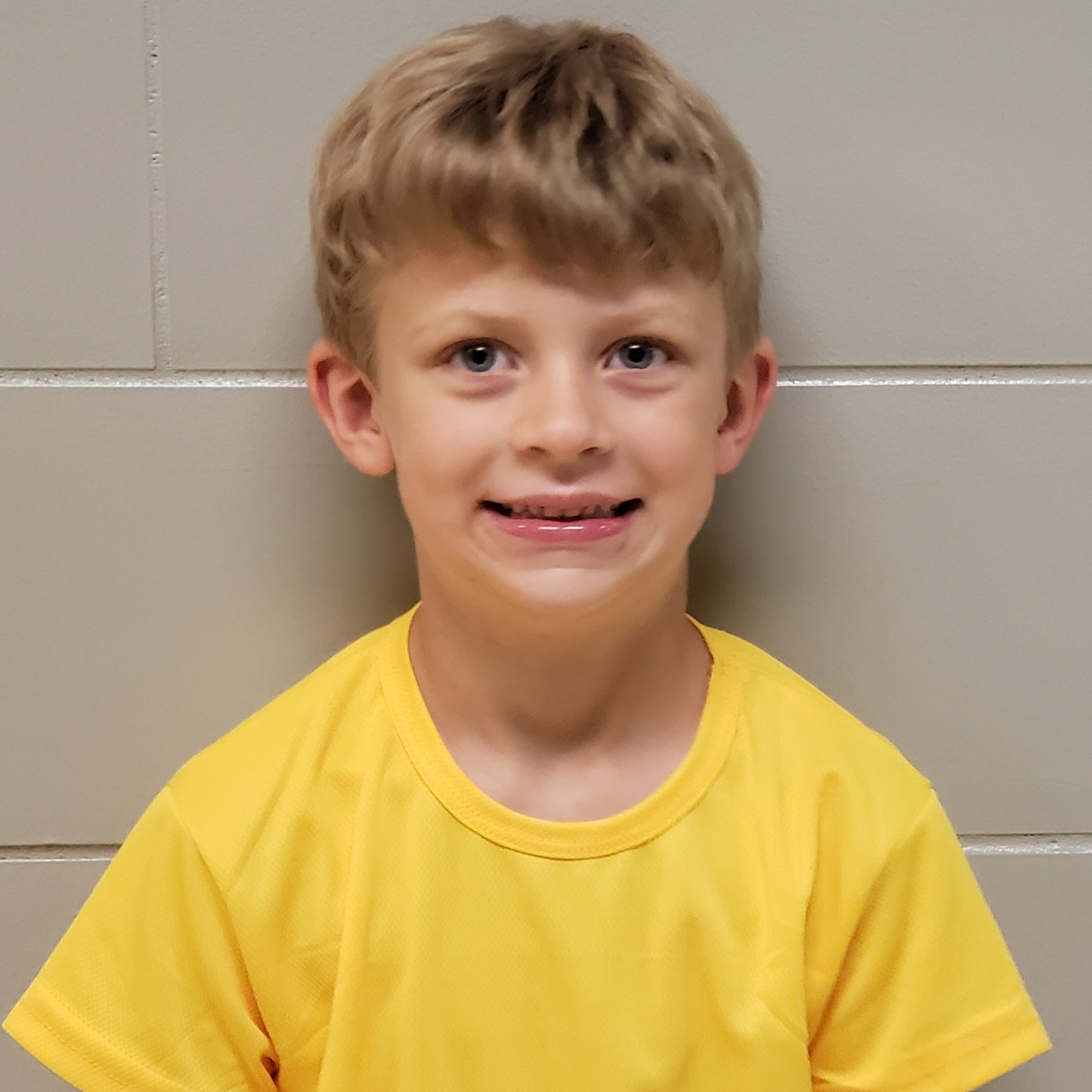 young boy with blonde hair wearing a yellow t-shirt