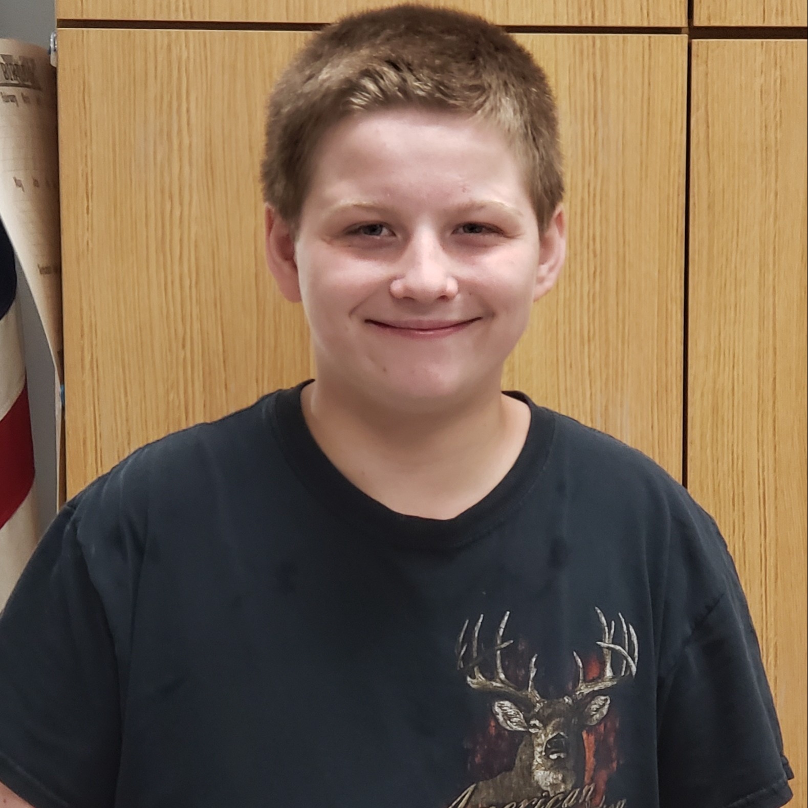 boy with dark blonde hair wearing a black t-shirt with a deer on it