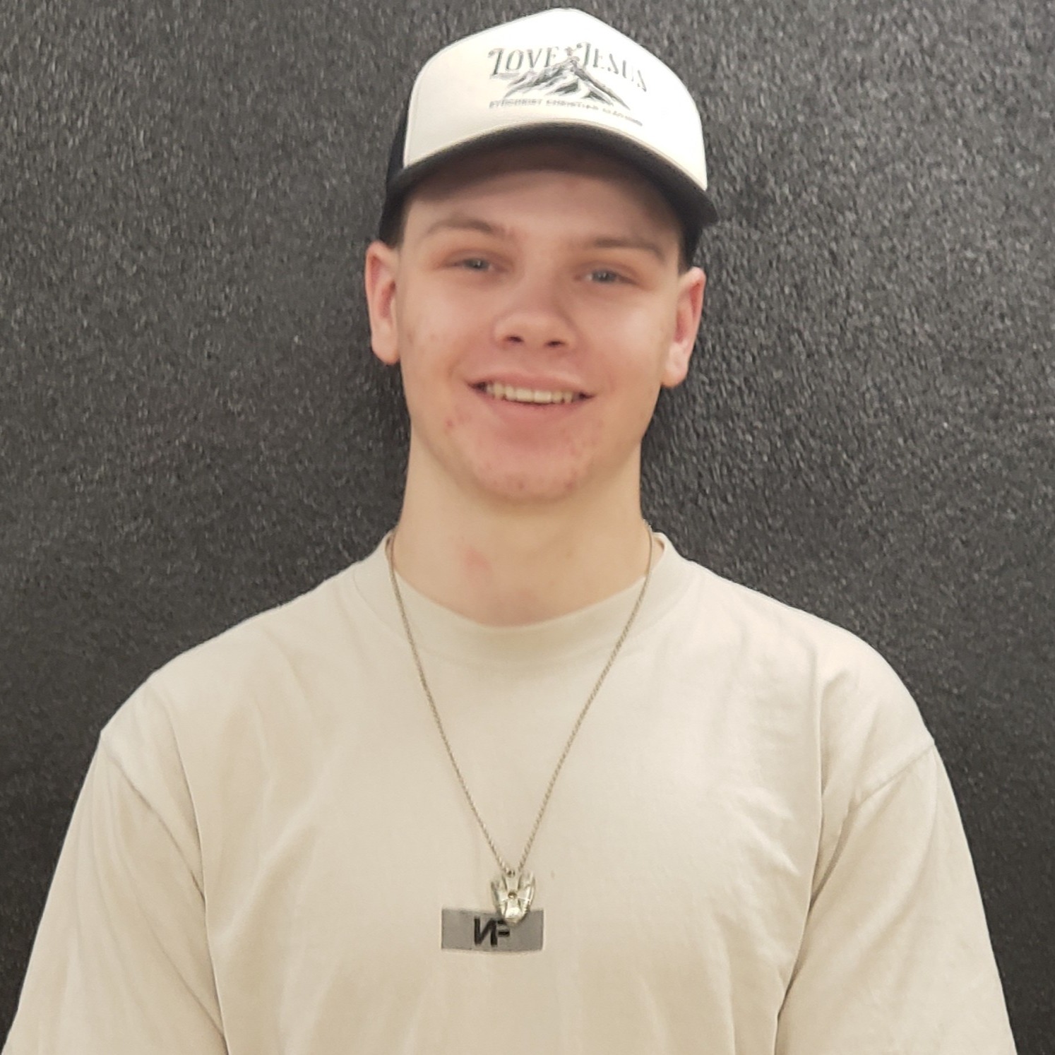 young man wearing ablack-and-white cap and a tan t-shirt