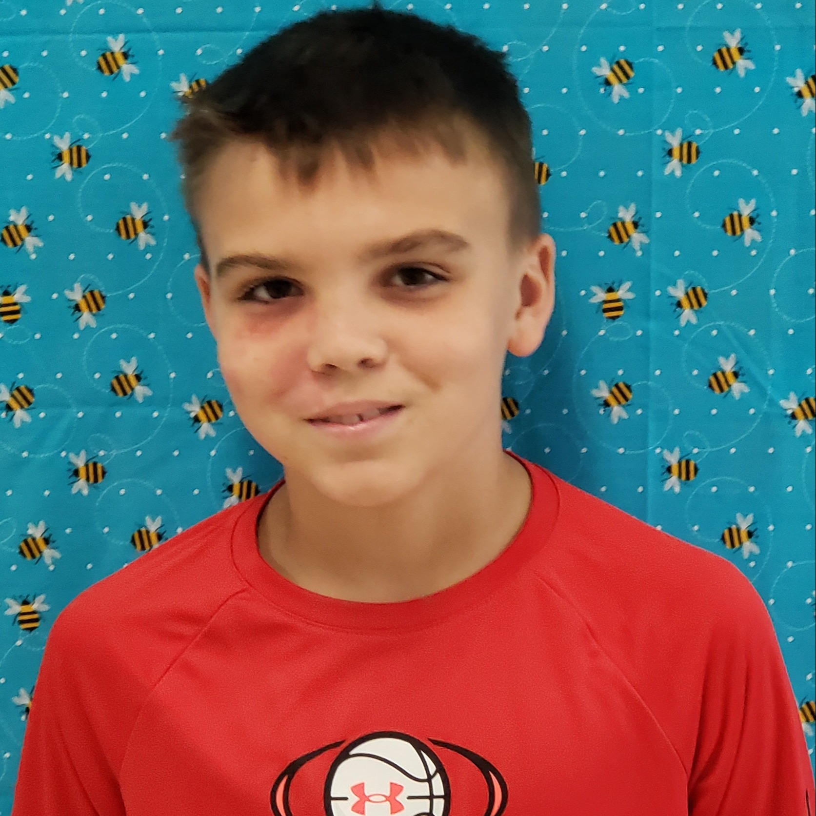 smiling boy with dark hair wearing a red t-shirt