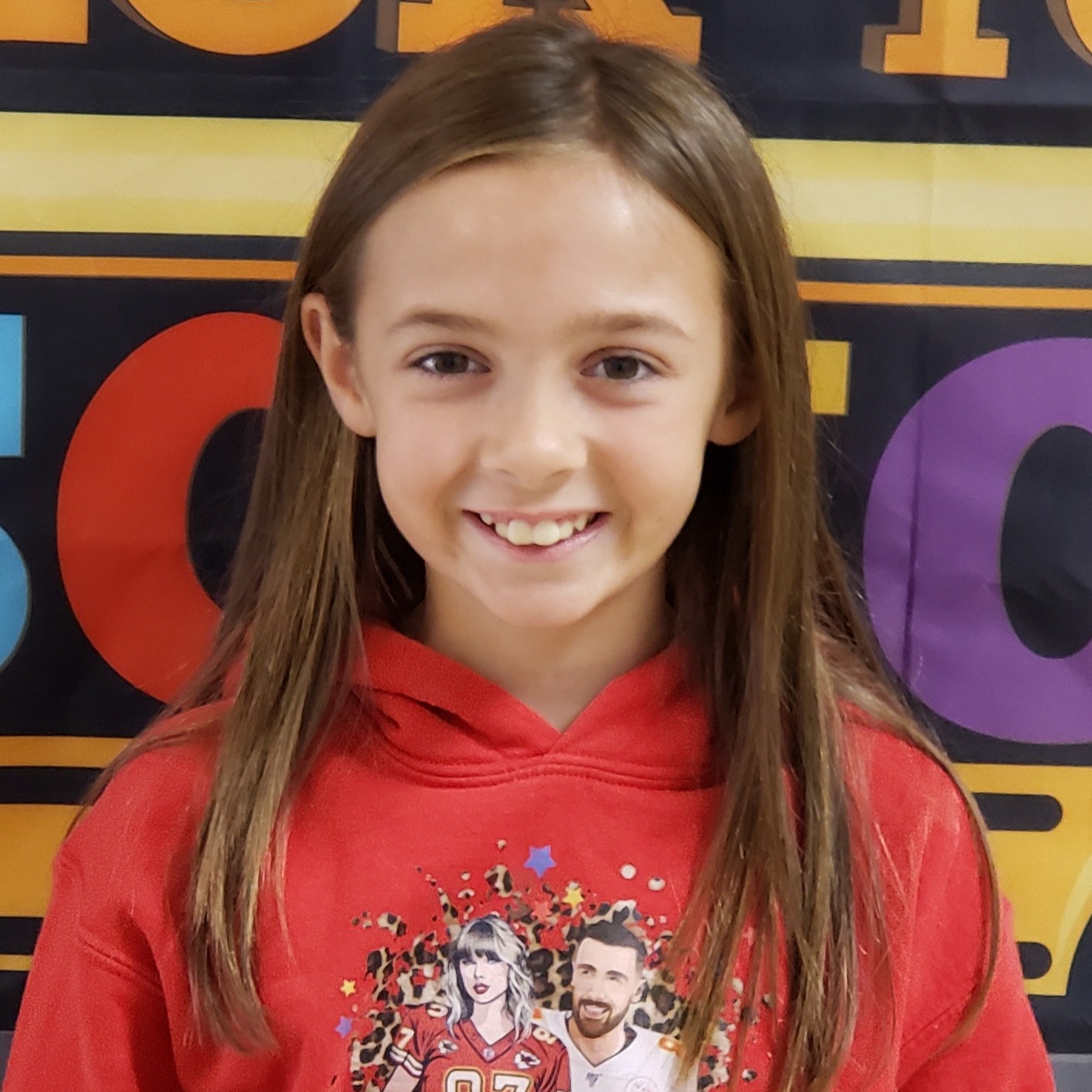 smiling girl with straight brown hair wearing a red hoodie