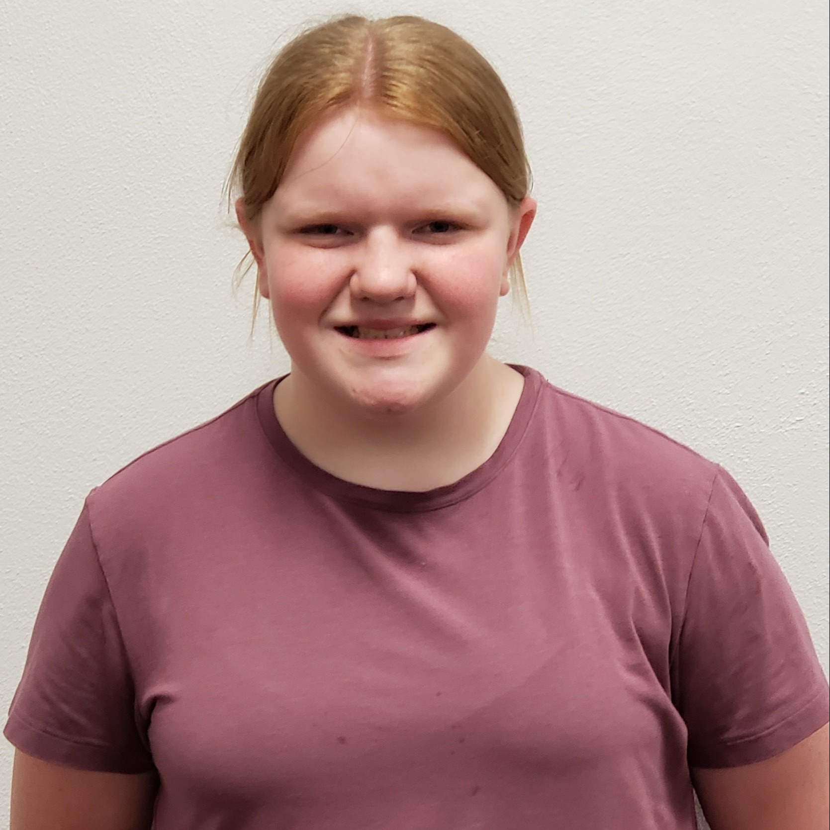 smiling girl with red hair wearing a mauve t-shirt