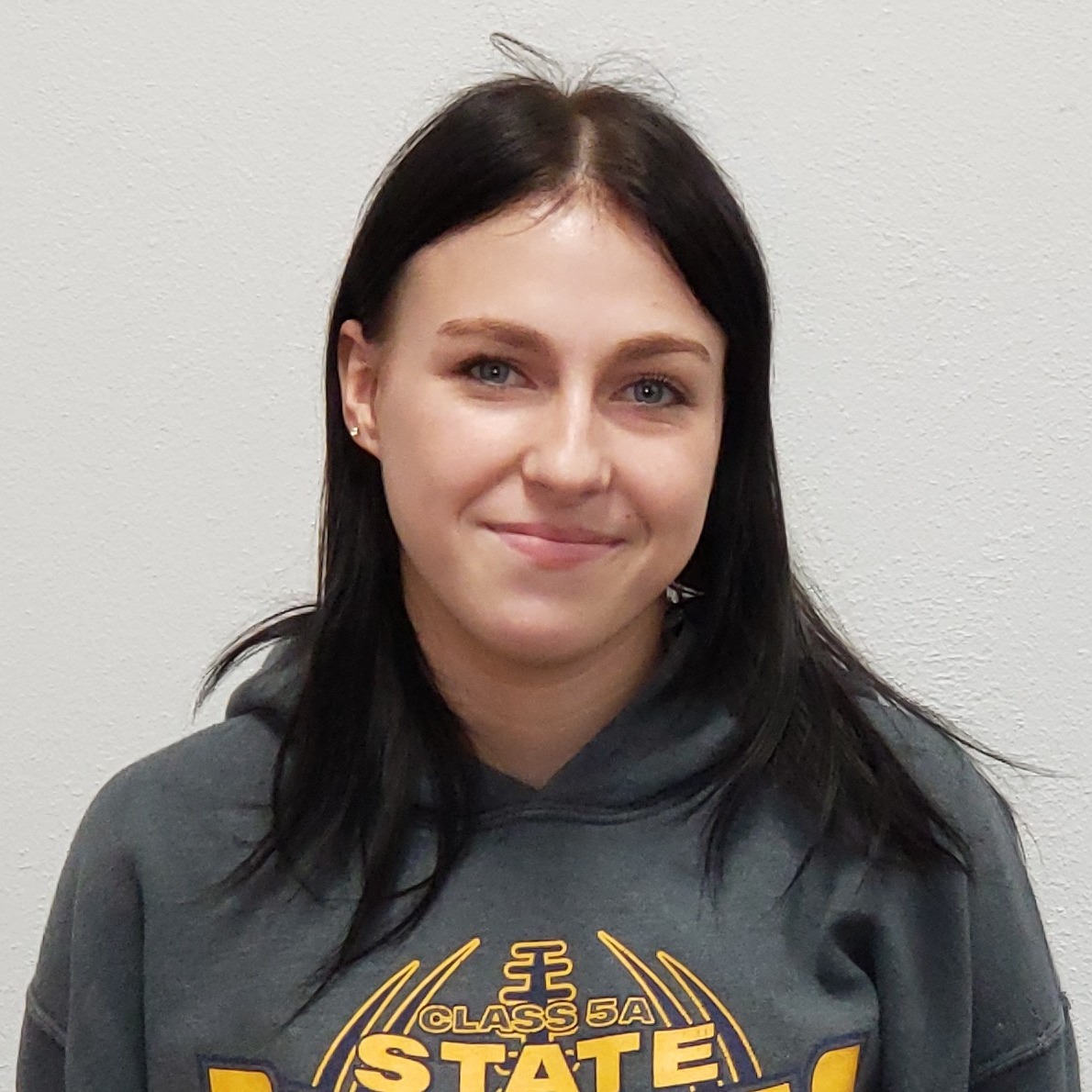 smiling young lady with black hair wearing a gray hoodie