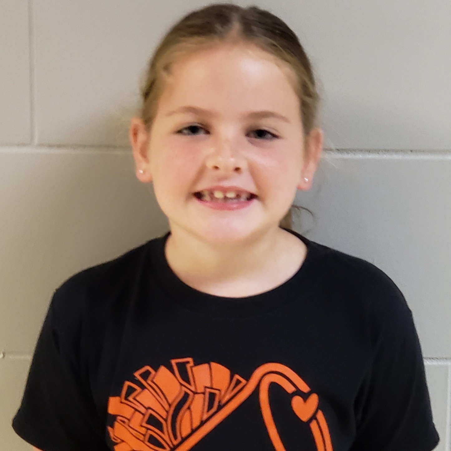 young girl with dark hair pulled back wearing a black t-shirt