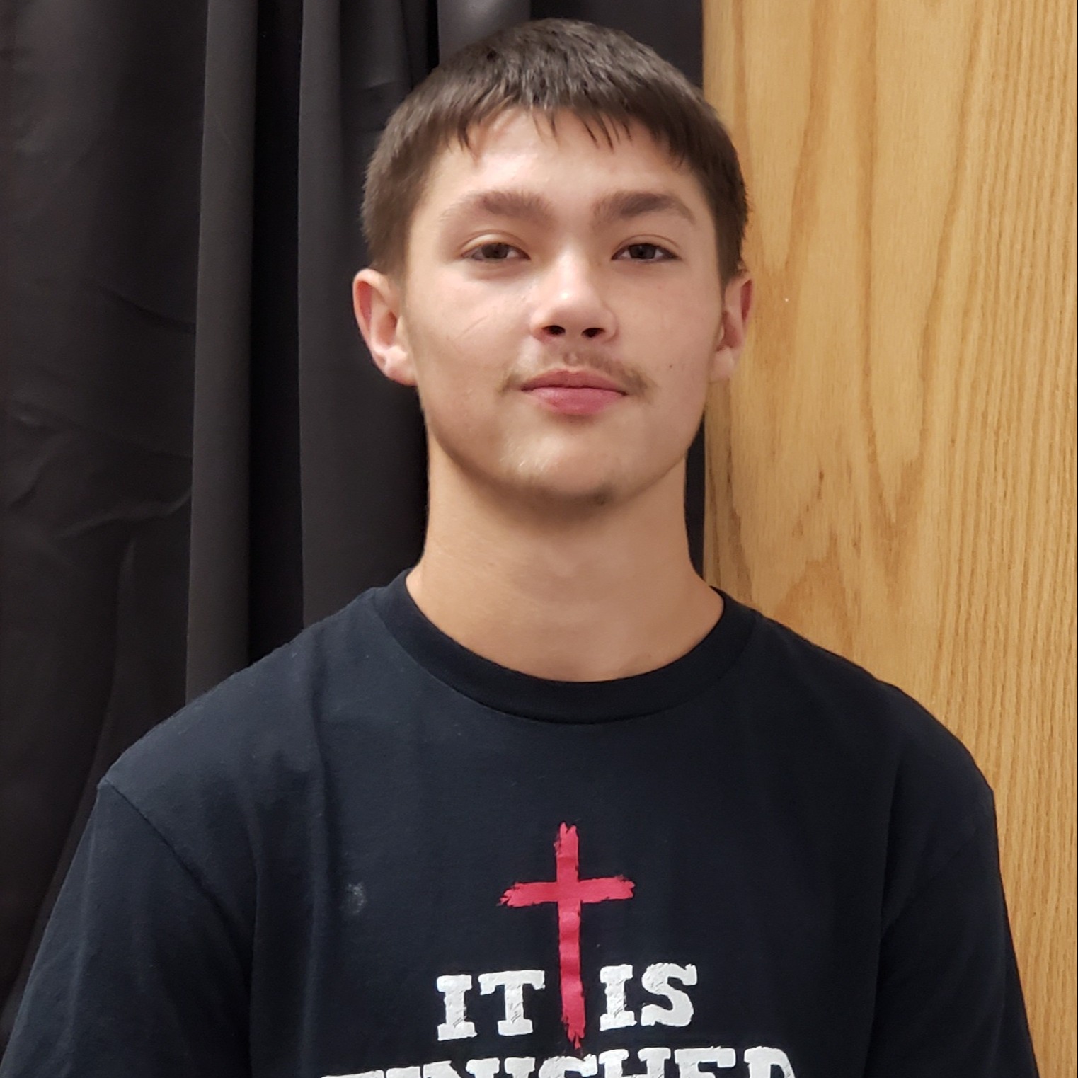 young man with brown hair wearing a black t-shirt