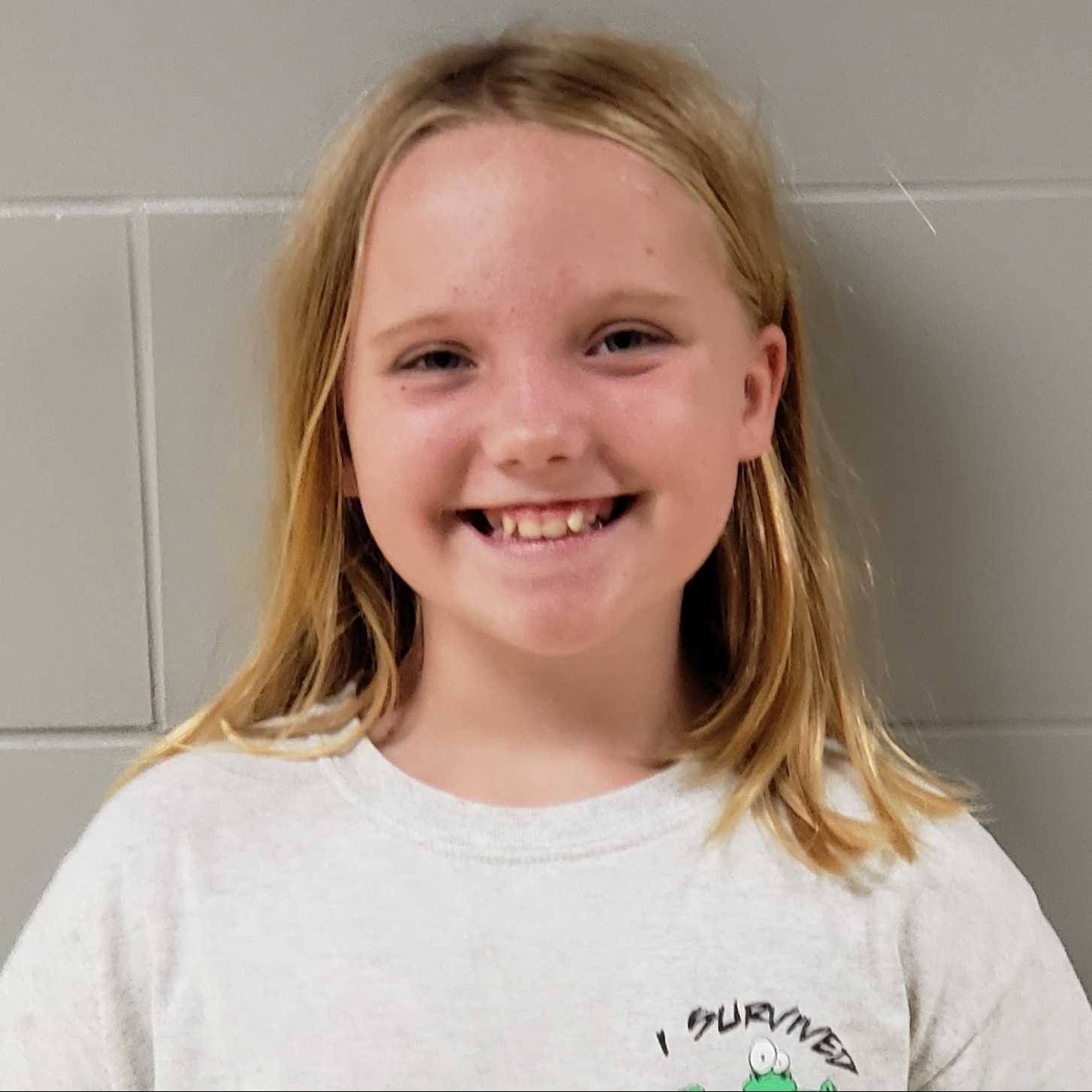 smiling girl with blonde hair wearing a white t-shirt