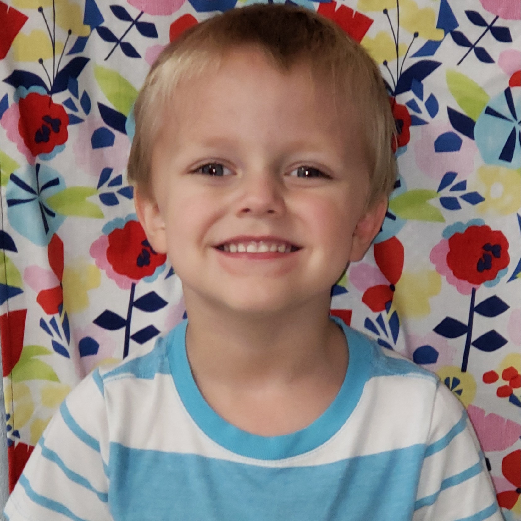 smiling little boy with blonde hair wearing a blue & white striped t-shirt